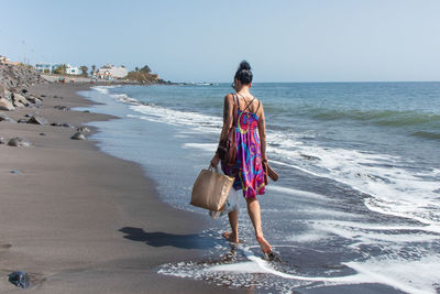 Rear view of woman on beach against sky