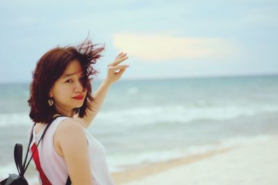 Side view portrait of young woman with tousled hair standing at beach