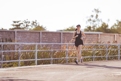 Full length of woman standing by railing against sky