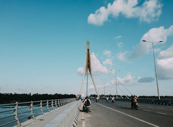 People on street by bridge against sky