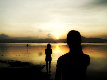 Silhouette of people on beach at sunset