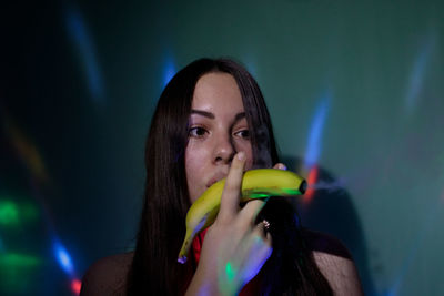 Digital composite image of beautiful young woman holding banana with smoke