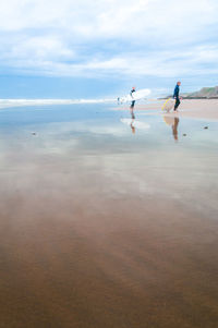 People at beach against sky