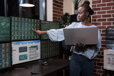 Side view of man using digital tablet while standing in factory