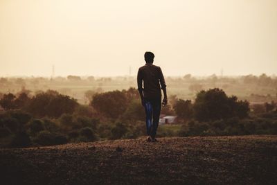 Rear view of man walking on field