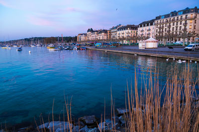 Sailboats in city by buildings against sky