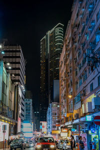 Illuminated modern buildings in city against sky at night