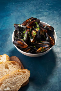 Boiled mussels in bowl with parsley and onion