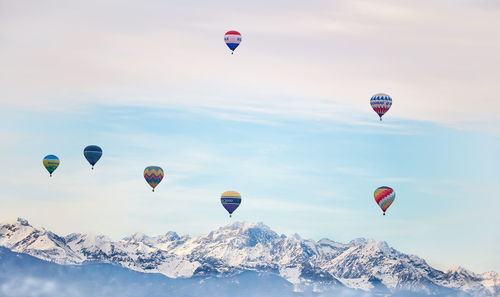 Hot air balloons flying over snow mountains against sky