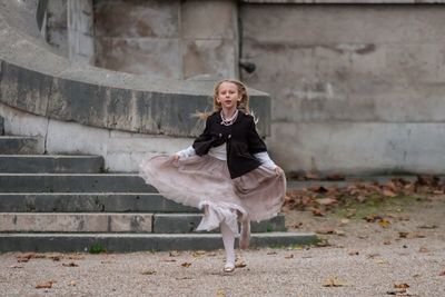 Portrait of girl holding dress while running on field