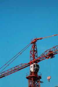 Low angle view of crane against clear blue sky