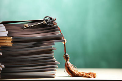 Stack of books with key at classroom against blackboard