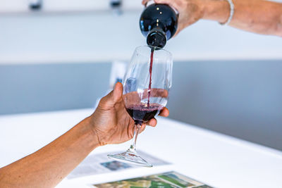 Midsection of person holding wineglass on glass of water