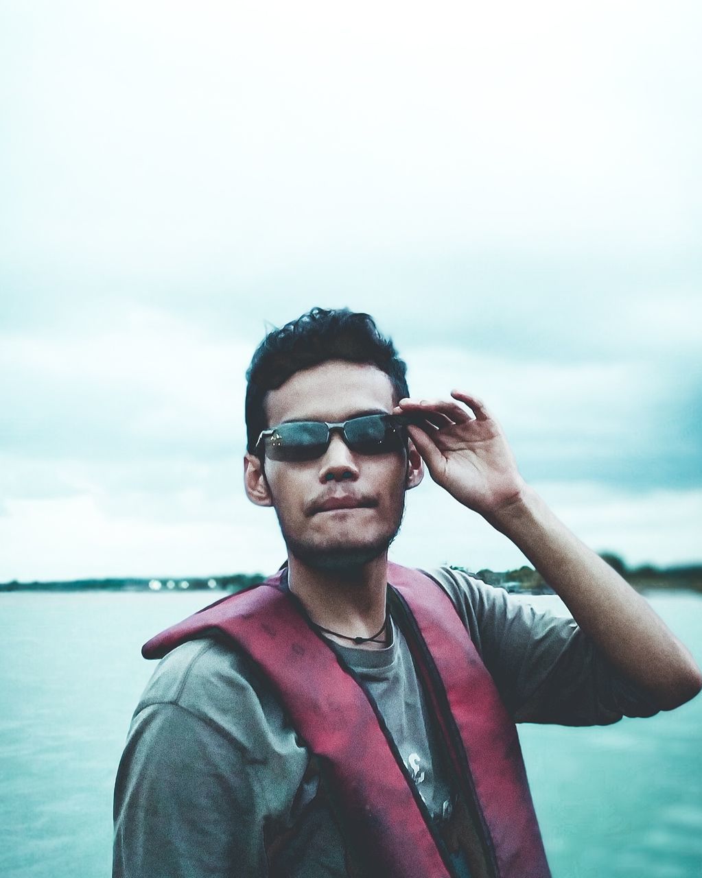 one person, water, sky, adult, portrait, blue, sea, young adult, fashion, nature, sunglasses, glasses, men, leisure activity, cloud, standing, waist up, casual clothing, copy space, looking, day, lifestyles, vacation, holiday, front view, outdoors, trip, headshot, beard, clothing, photo shoot, looking away, travel, relaxation, facial hair, cool attitude, beach, person, focus on foreground, emotion, jacket, spring, smiling, land