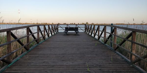 Pier over sea against sky during sunset