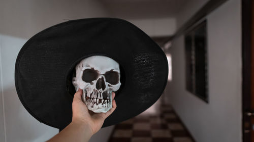 Cropped hand holding skull with hat