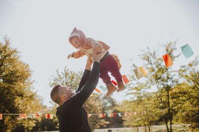 Father picking up boy wearing animal costume on sunny day