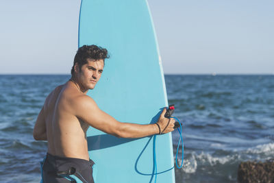 Young man standing on beach against sky