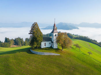 Aerial drone shot of sveti tomaž church in Škofja loka in slovenia with misty mountains