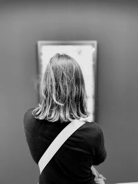 Rear view of woman standing against wall in museum 