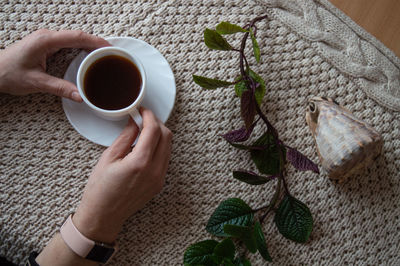 Cropped hand of woman holding coffee on table