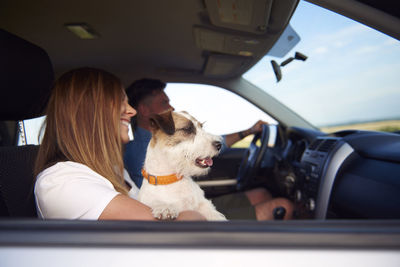 Couple with dog sitting in car