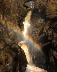 Scenic view of rainbow over waterfall