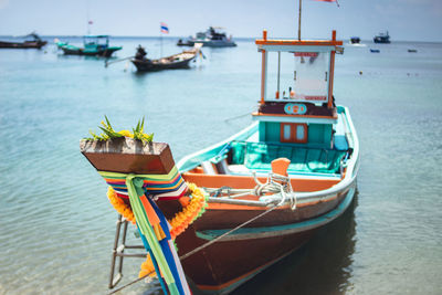 Boat moored on shore at beach against sky