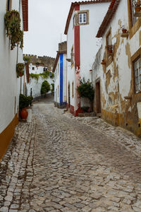 Narrow street amidst buildings in medieval city town of obidos