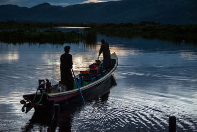 People in boat moving on lake during sunset