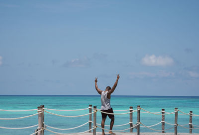 Man standing on pier over sea against sky