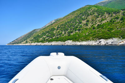 Boat sailing in sea against clear blue sky