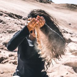 Woman with falling sand from hands at desert