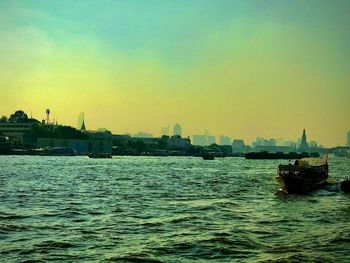 Boats sailing on sea against buildings in city against sky