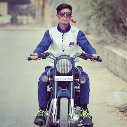 Portrait of young man riding motorcycle on road