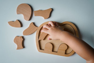 A child hand is playing with wooden puzzles.
