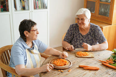 High angle view of senior couple chopping carrots on table at home