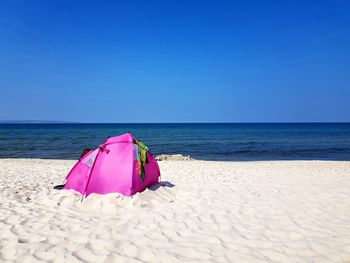 Pink umbrella on beach against sky