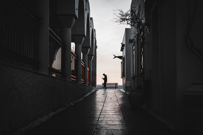 Rear view of people walking on footpath amidst buildings