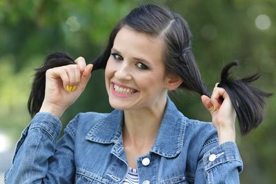 Portrait of smiling young woman against trees