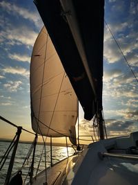 Sailboat sailing on sea against sky during sunset