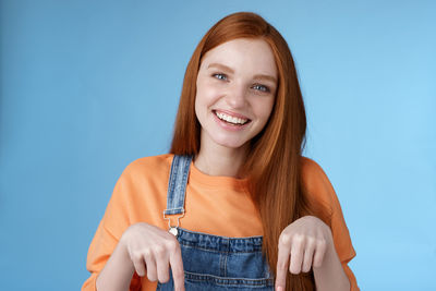 Portrait of a smiling young woman against blue background