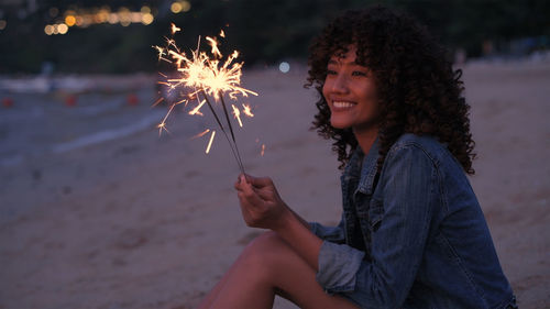 Young woman holding umbrella at night