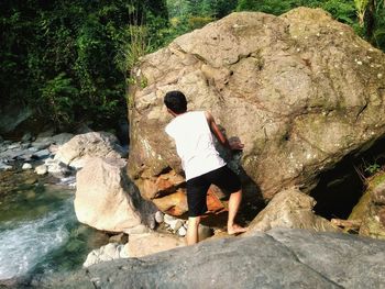 Rear view of woman with dog standing on rock