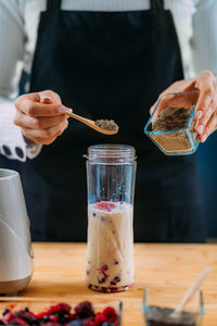 Midsection of person pouring wine in glass on table