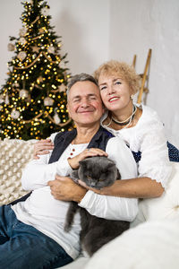 Portrait of smiling young woman holding christmas tree