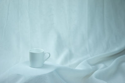 Close-up of coffee cup on bed
