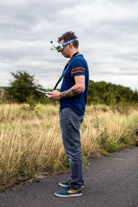 Side view of young man standing against plants