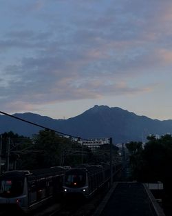 Cars on mountain against sky during sunset