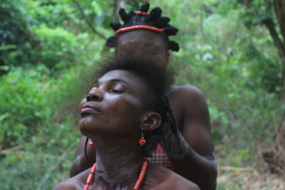 Woman braiding friend hair in forest